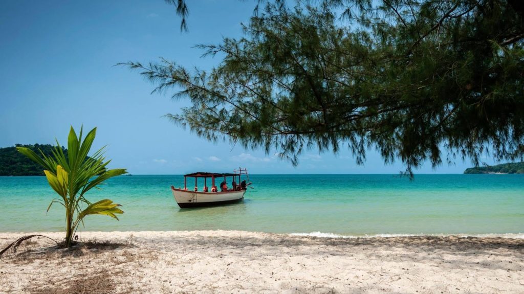 Barco de madera tradicional en una playa de arena blanca de Koh Ta Kiev